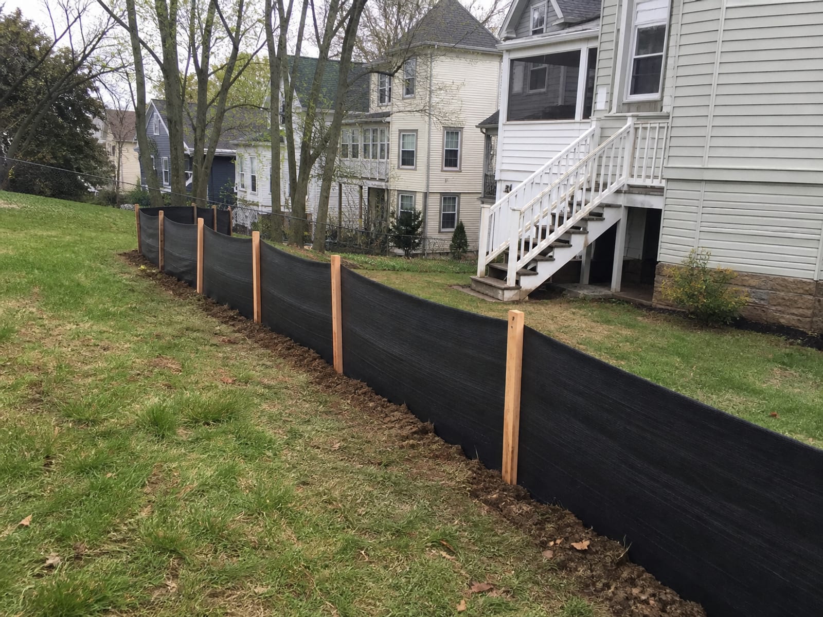 Silt fence and staked sediment barrier installed along the downhill edge of a residential work area before any soil has been disturbed