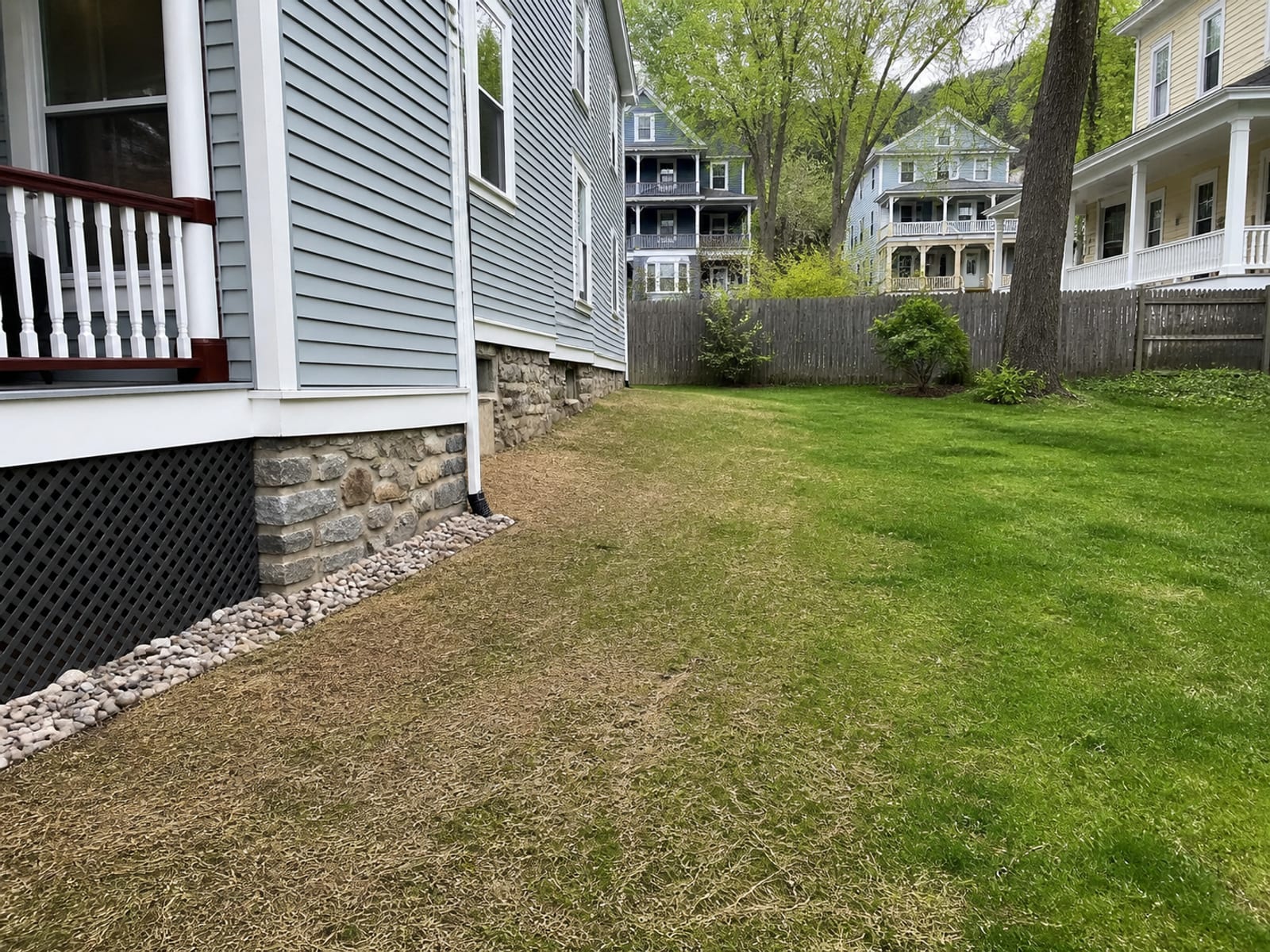 Restored residential lawn after regrading, with fresh topsoil and seed and a deliberate fall carrying surface water away from the house
