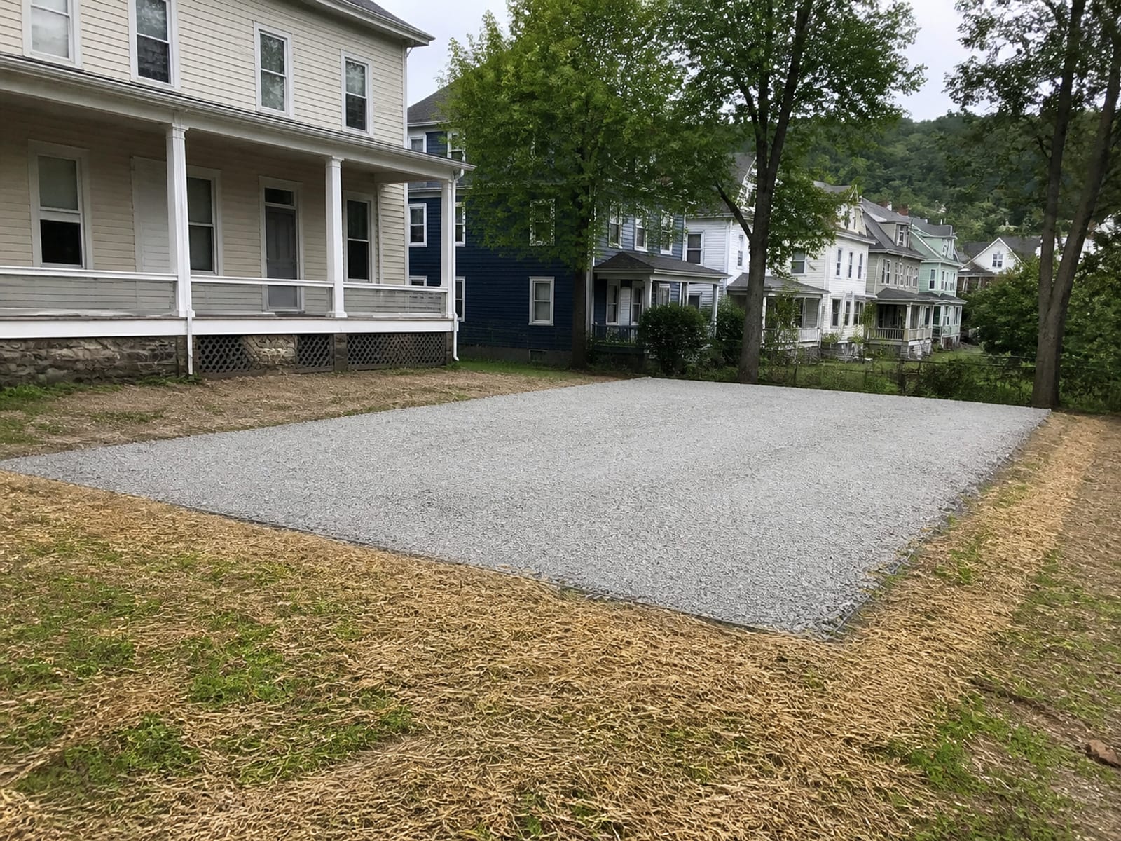 Compacted and level building pad with placed aggregate base, ready for foundation work, with surface drainage falling away from the pad edges