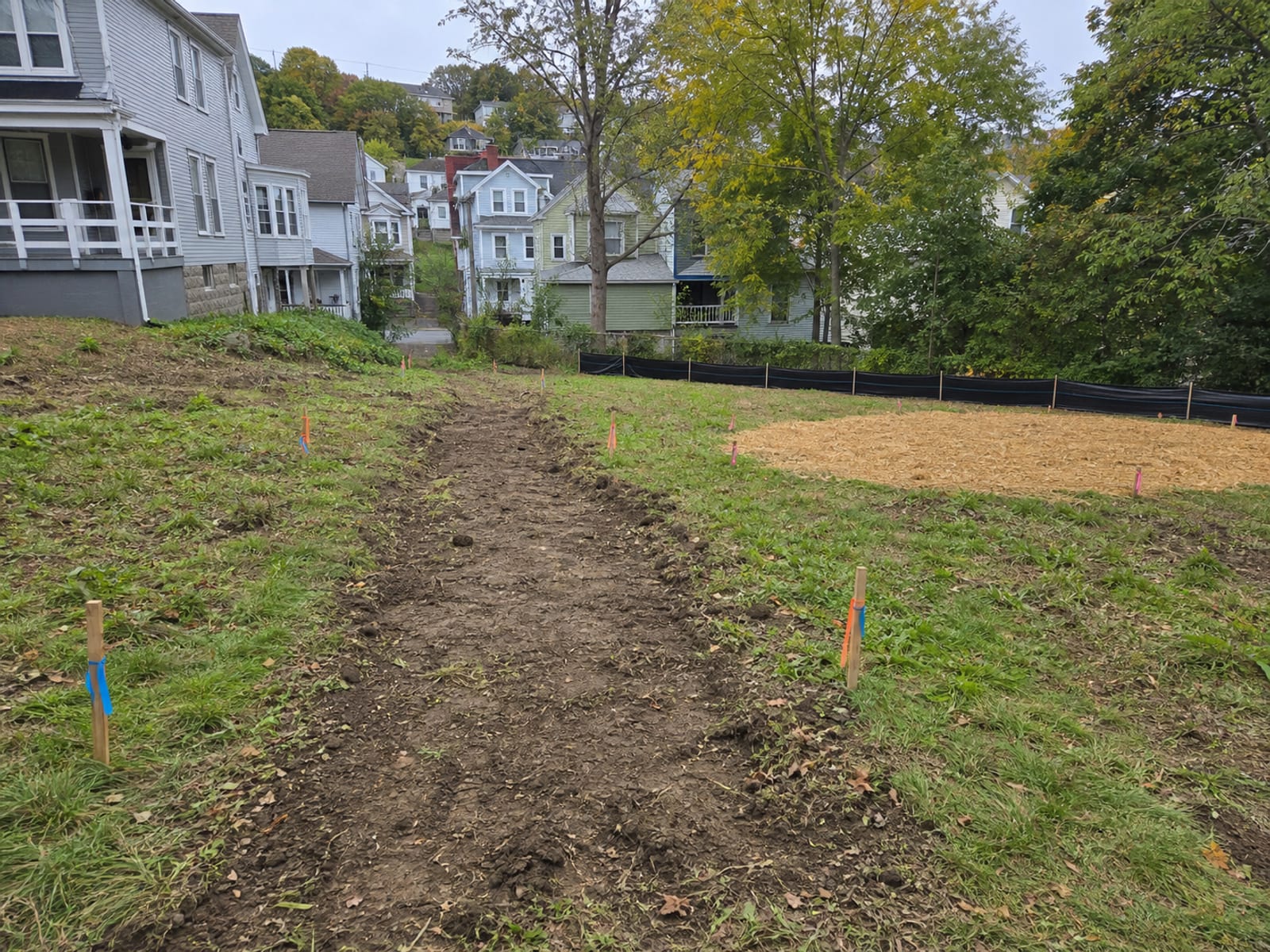 Residential building lot with the access route marked, a stockpile area set aside, and sediment controls installed along the downhill boundary before clearing