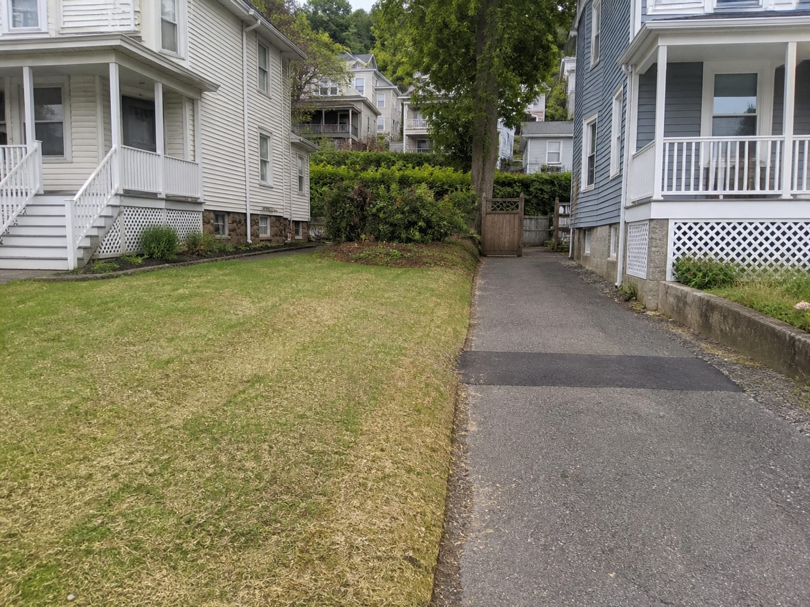 Restored residential driveway and lawn after utility trenching, with the backfilled trench line compacted and the surface patched and graded