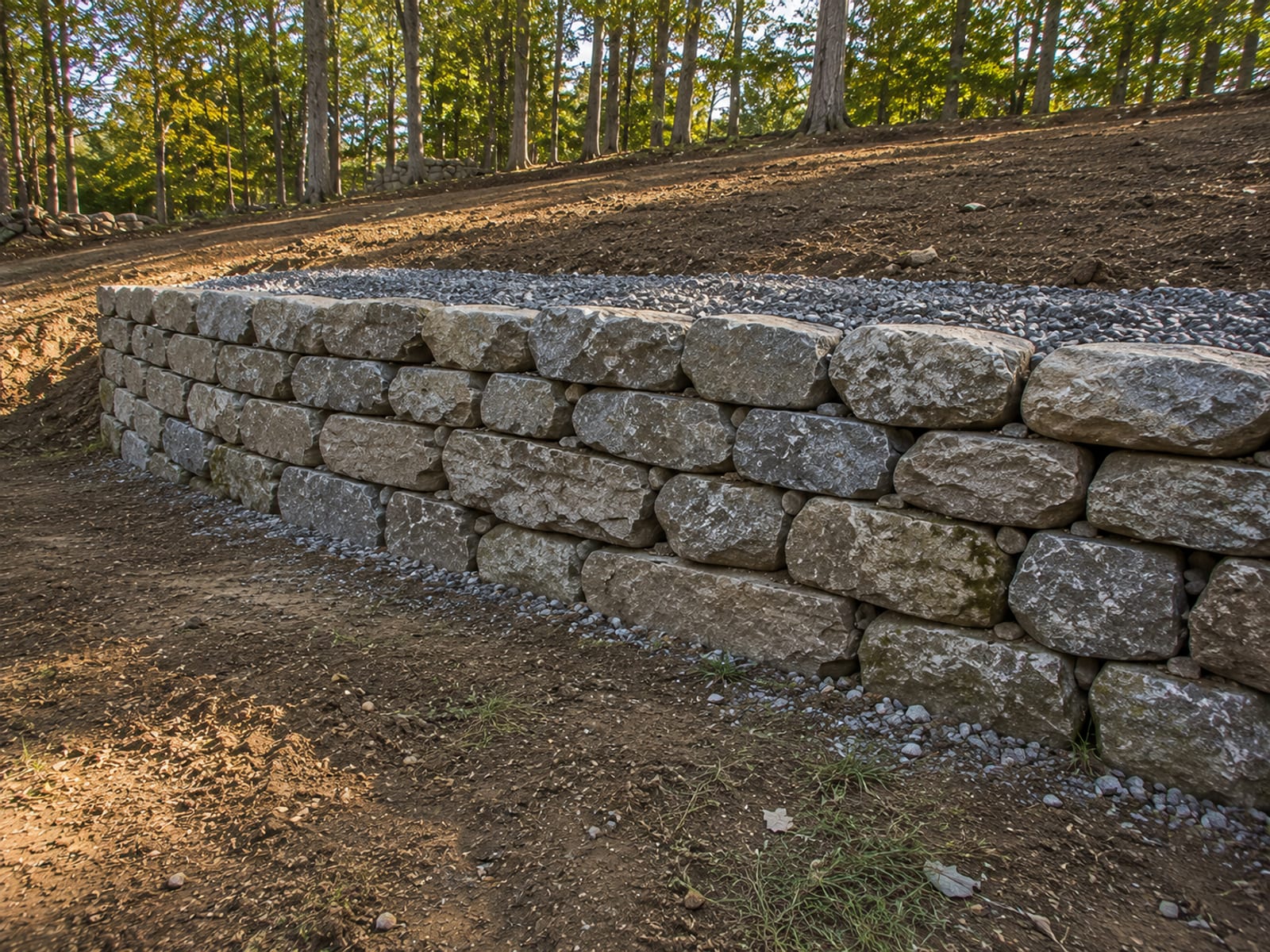 Newly built dry-stacked stone retaining wall terracing a sloped residential yard in Bridgewater CT