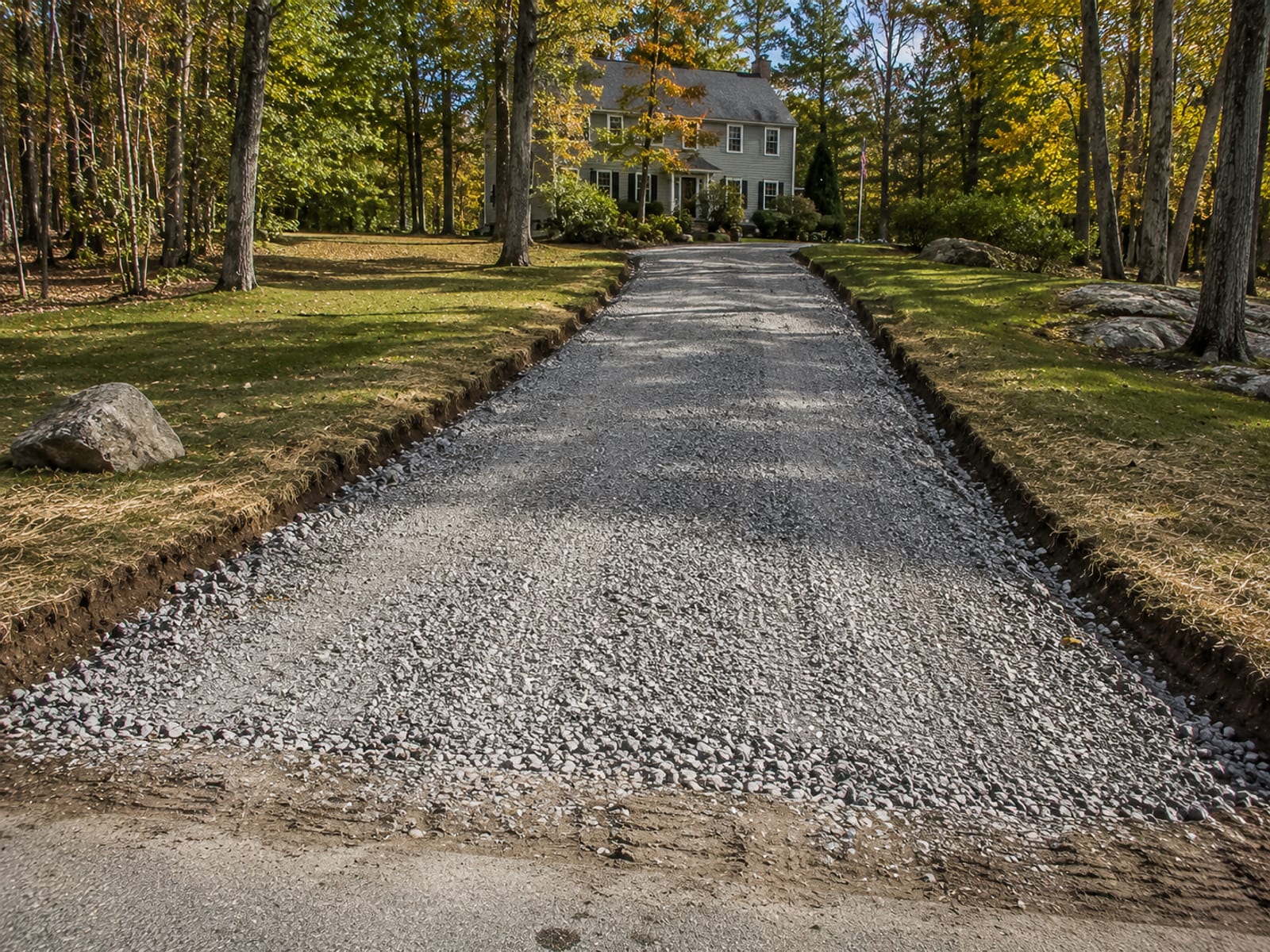 Freshly excavated and compacted gravel base for a residential driveway in Bridgewater CT with wooded surroundings