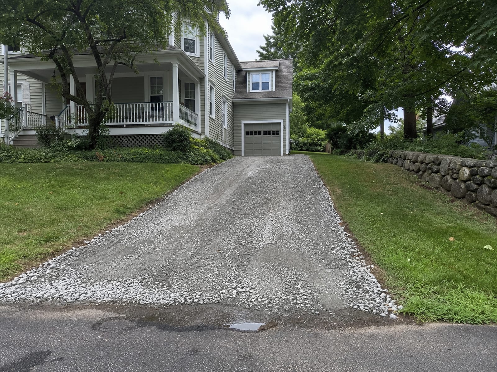 Residential driveway stripped back and rebuilt with fresh compacted crushed stone running from the street up to an attached garage