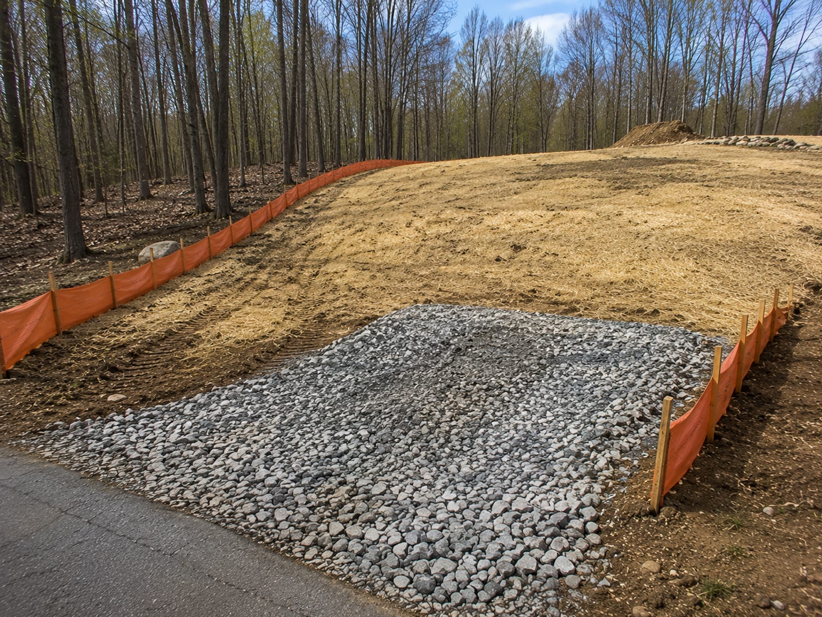 Finished erosion control installation on a residential construction site with silt fence, mulch, and stabilized entrance