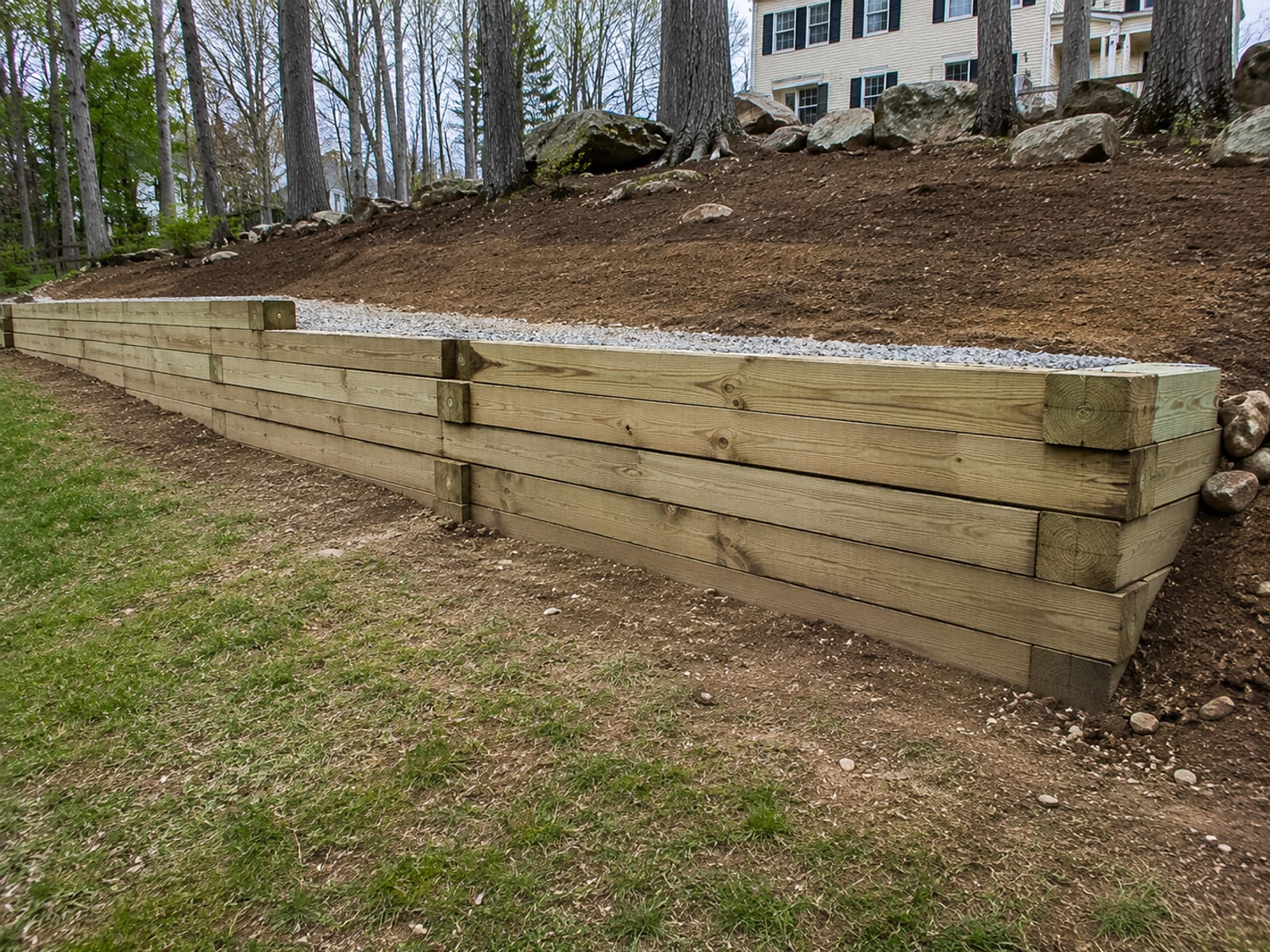 Newly completed landscape timber retaining wall holding back a sloped yard on a Connecticut residential property