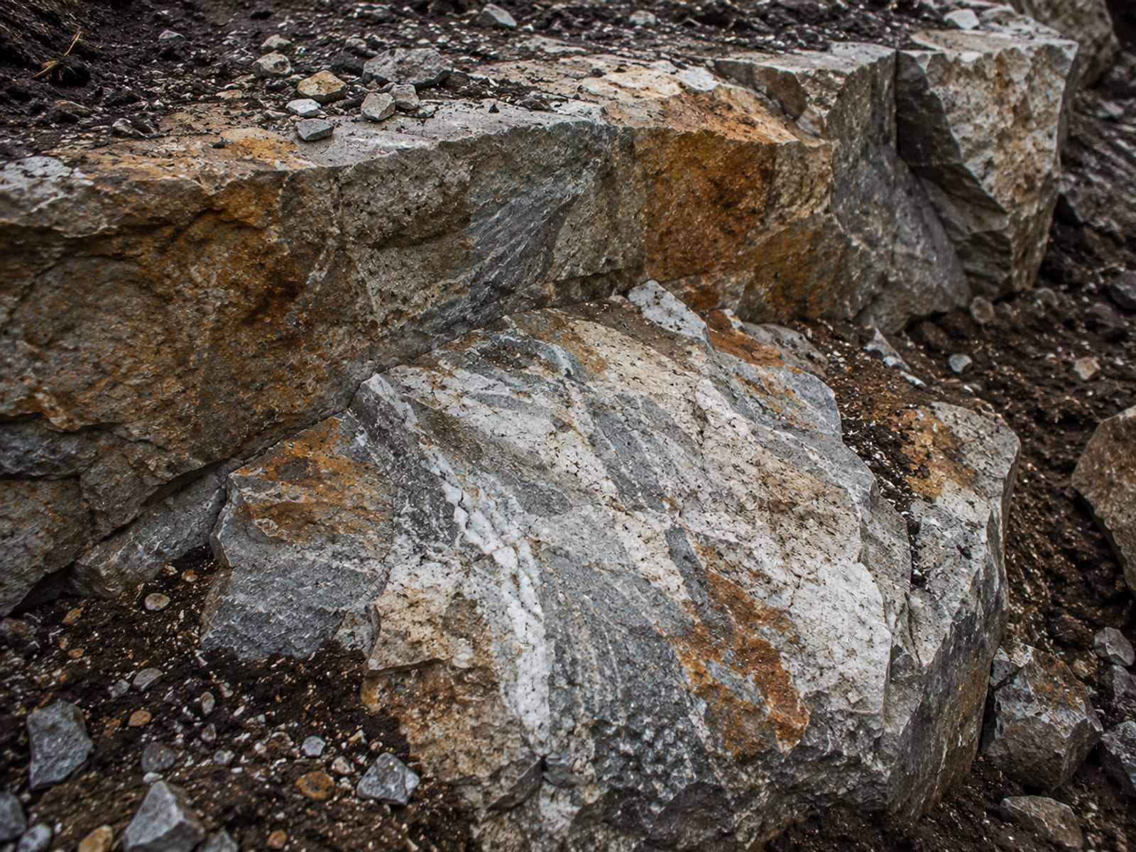 Close detail view of fractured granite ledge rock with fresh break faces and iron-stained stone surfaces at a Connecticut dig site