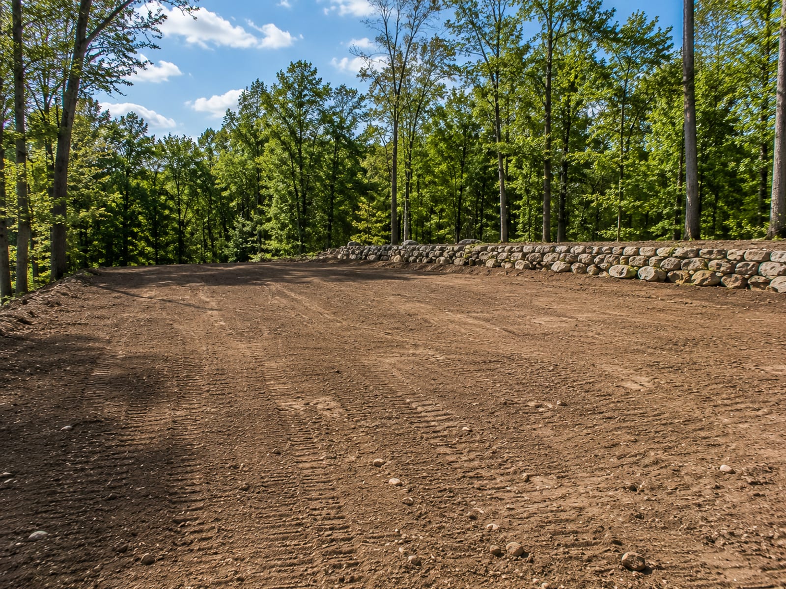 Freshly graded and rock-cleared residential lot ready for construction with smooth compacted soil surface