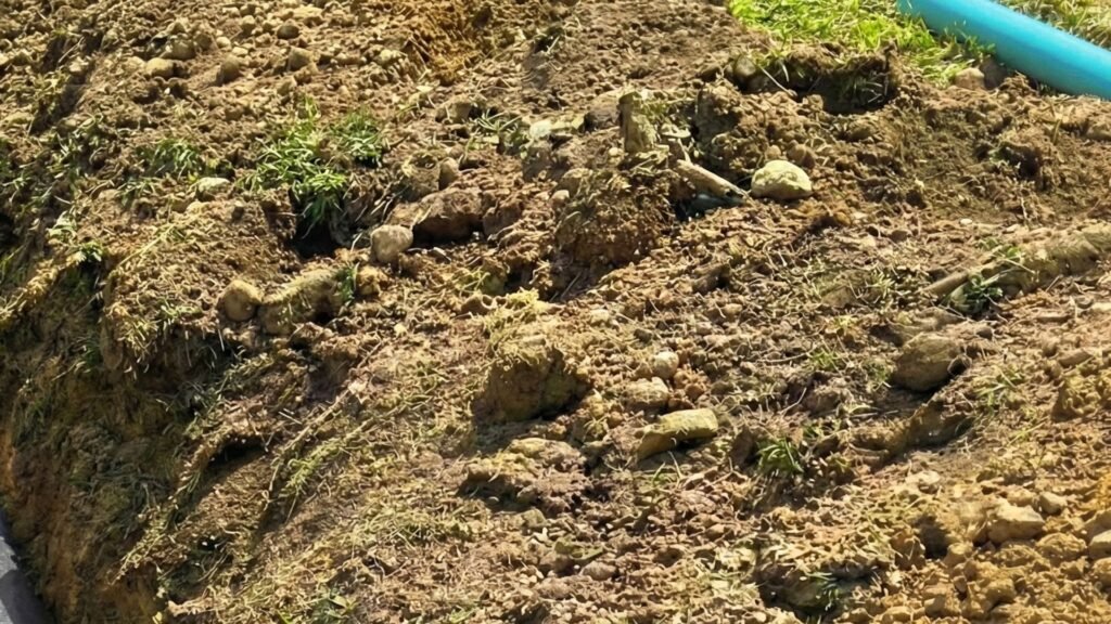 Soil backfill over residential drainage trench during installation process