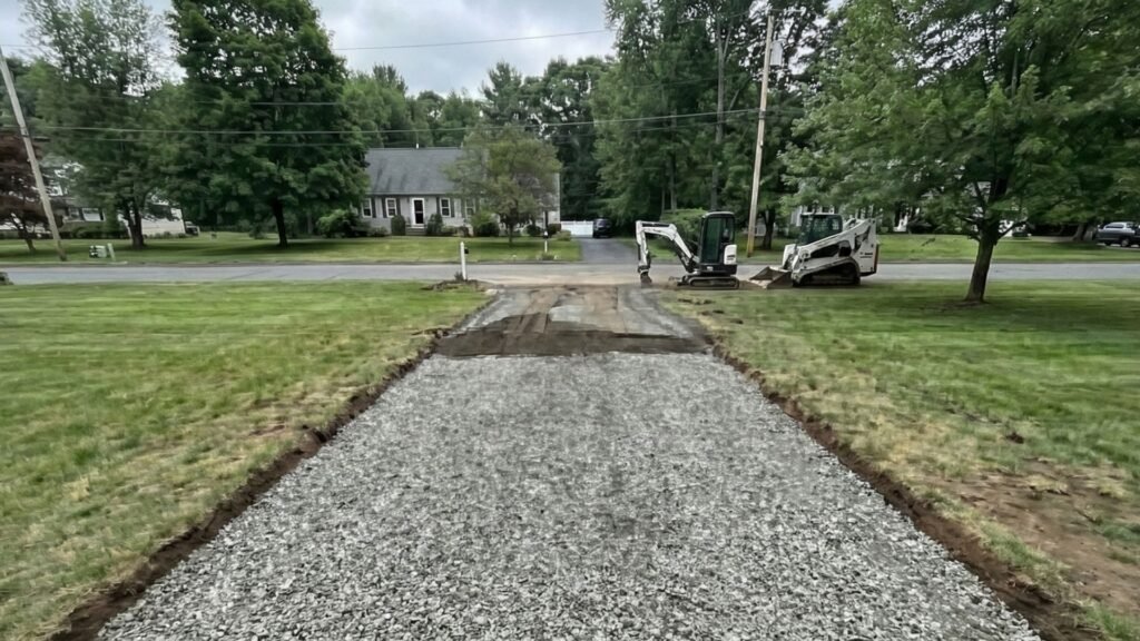 Gravel driveway base installed and graded between lawn edges on a residential property