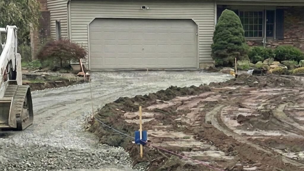 Worker marking driveway layout during residential excavation and base preparation