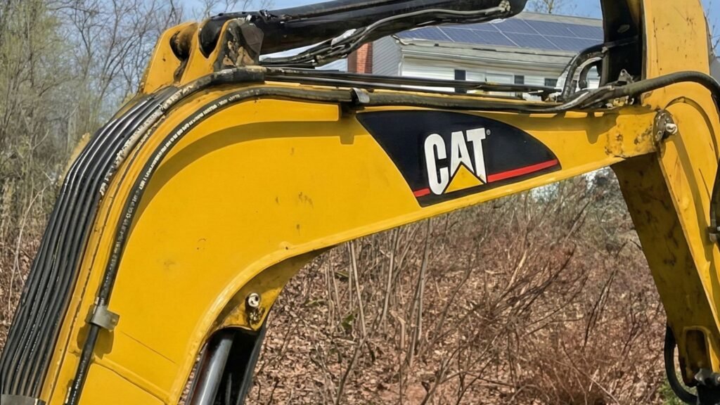 Close up view of compact excavator arm and hydraulic lines during residential excavation